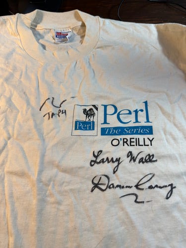 A cream colored “Perl the series” O’Reilly tee shirt autographed by Larry Wall, Damian Conway, and Randal Schwartz