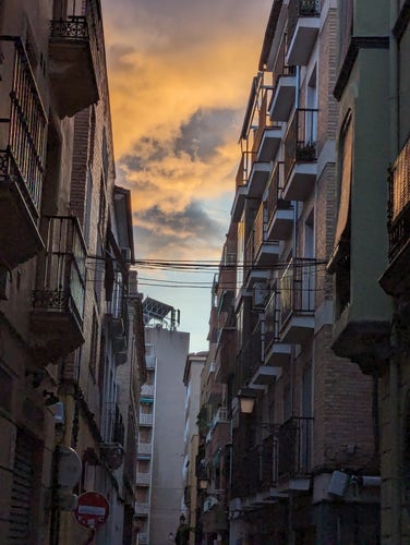 Stormy clouds lit by a dying sun at the end of a city centre residential street in Granada.