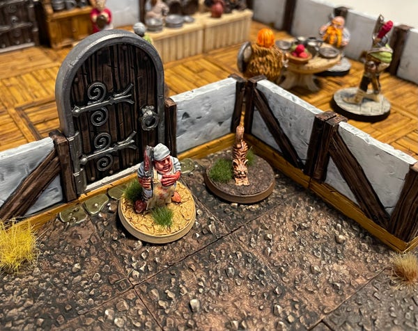 3D printed miniature scene. A butcher and cat stand surprised outside an inn