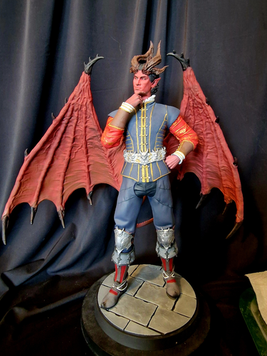 Figurine en résine du personnage de Raphaël dans le jeu vidéo Baldur's Gate 3. Un homme imposant en belle tenue, sûr de lui. Sa peau est rouge, tout comme les larges ailes nues et à pointes de son dos, complétés par de grandes cornes marrons sur son crâne.