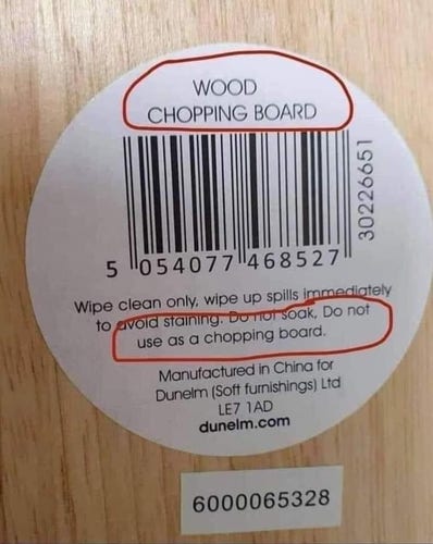 A close-up of the sticker on a wooden cutting board. At the top of the sticker is the text “wood chopping board”. Further down is standard care instructions, followed by the contradictory text “do not use as a chopping board”.