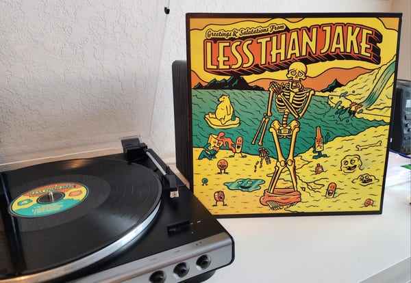 Less Than Jake - Greetings and Salutations album cover next to a record player. Vinyl is black.