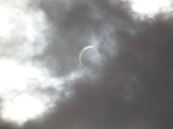 A solar eclipse partially obscured by clouds.