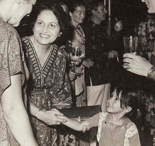 A black and white photo, from I think the late 1960s or early 1970s, of a caucasian woman with black hair, wearing an Indonesian batik dress, smiling openly and beautifully at the person next to her.

But she is holding, with both hands, the outstretched arm of a small child who beams up at the woman with delight and joy.