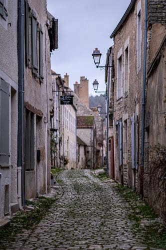 Photo of a small cobbled street, with a sign on one wall reading “Le Gratin Mondain”.