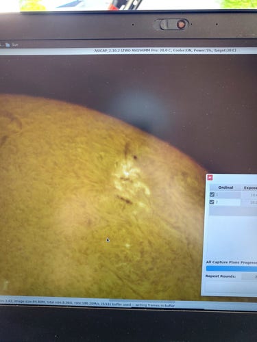 Photo of a laptop screen with a view of the sun's surface. There's a bright sunspot with a long smudge coming out of the top