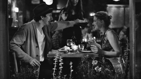 Still frame from Frances Ha. A man and woman are sitting in a restaurant, cheerfully.