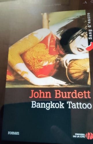 Couverture du livre de John Burdett, Bangkok Tatoo. Une jeune femme asiatique allongée sur le côté, avec un regard nostalgique.