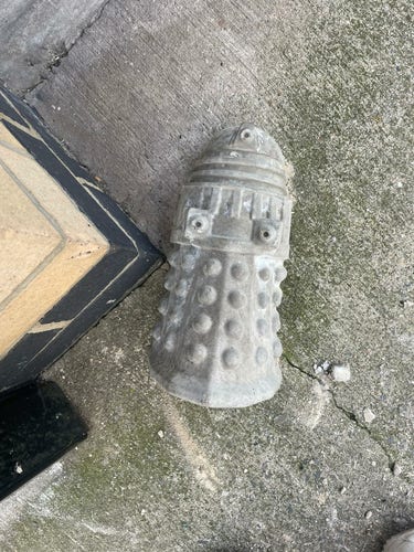 A grey dalek figurine lying on the floor outside the Vagina Museum. 