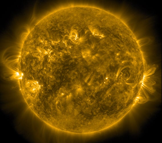Die ganze erdzugewandte Seite der Sonne in gelber Farbe. An den Rändern links und rechts senden Aktive Regionen Strahlen aus, die riesige Bögen formen.
