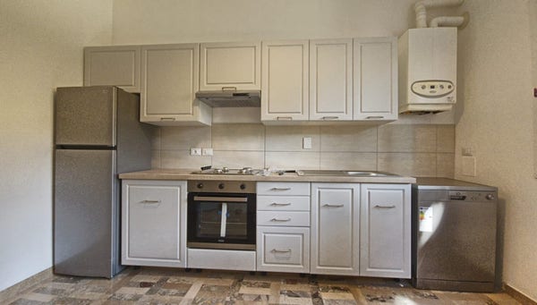 Cucina lineare con ante e cassetti grigi, piano in rovere, frigo e lavastoviglie in acciaio satinato
