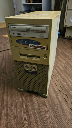 A sun Ultra 10 tower. It is significantly yellowed from the (actual) .  The front has an OpenBSD sticker that is somewhat askew.

It looks like it would smell like a taxi dispatcher office, even though it doesn't.