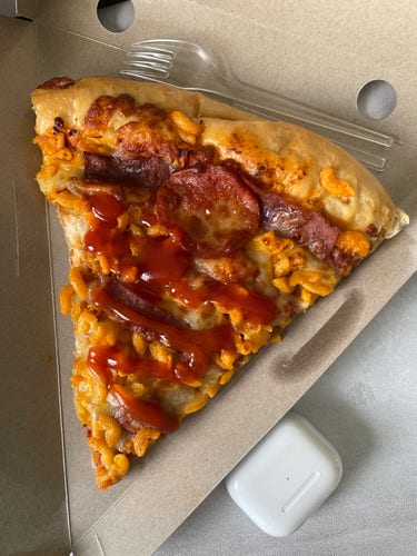 Overhead shot of a slice of Mac and cheese pizza with salami and tomato sauce