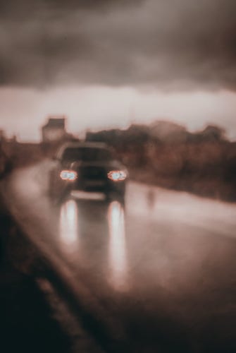 Intentional unscharfes Foto eines Autos, das bei Regen auf die Kamera zufährt