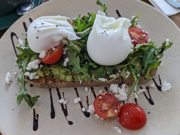 Smashed avocado on toast with poached eggs and rocket and tomato