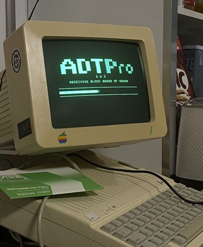 An Apple IIc running ADTPro. The CRT monitor shows an ongoing data transfer.
