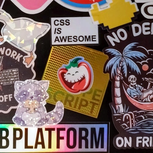 The happy pepper sticker stuck on top of a glitzy golden typescript sticker surrounded by lots of other web dev related stickers 