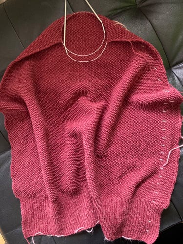 handgestricktes Rückenteil eines Pullovers in warmem Rot, in Perlmuster, mit Markierungen am Rand