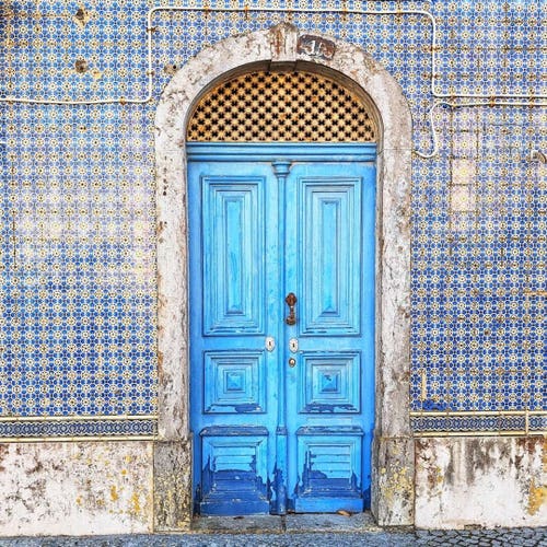 Bright blue weather-worn door surrounded by Portuguese tiles.