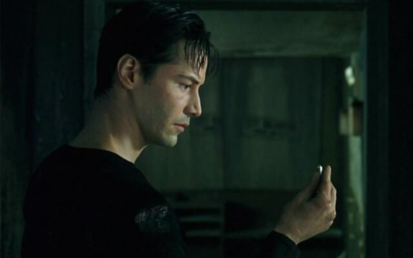 Neo thoughtfully examines a single bullet he holds.