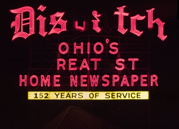 A photo of a red neon sign shining at night, with the text DISPATCH OHIO'S GREATEST HOME NEWSPAPER 152 YEARS OF SERVICE

The letters P, A, G and E are dark in the words Dispatch and Greatest.