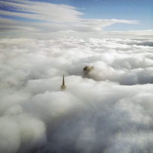 Aerial image of the transamerica tower and 555 California peaking above the fog in San Francisco. 