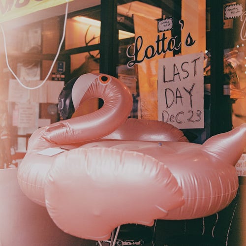 a scan of a square color film negative of an inflatable flamingo. in the background it says 'Lotta's: Last Day Dec 23' 