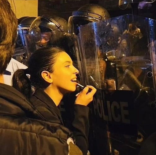 Frau schminkt sich in der Reflexion eines Polizeichildes.
Die Polizisten tragen martialische Uniform während der Proteste in Georgien.