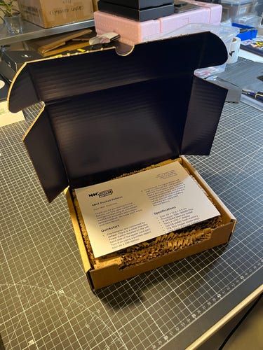 opened pocket reform cardboard box, with paper based filling material and folded quickstart manual