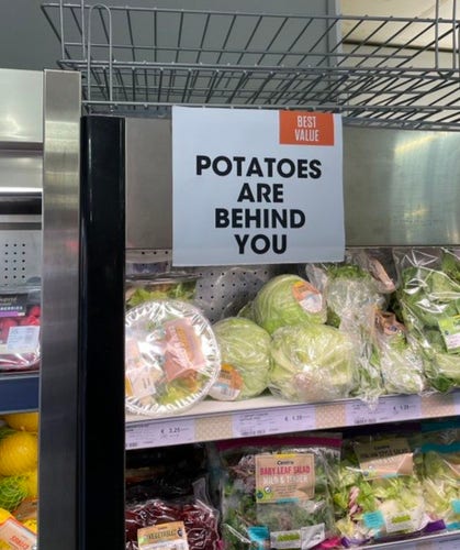 Sign in a grocery store that reads "Potatoes are behind you"
