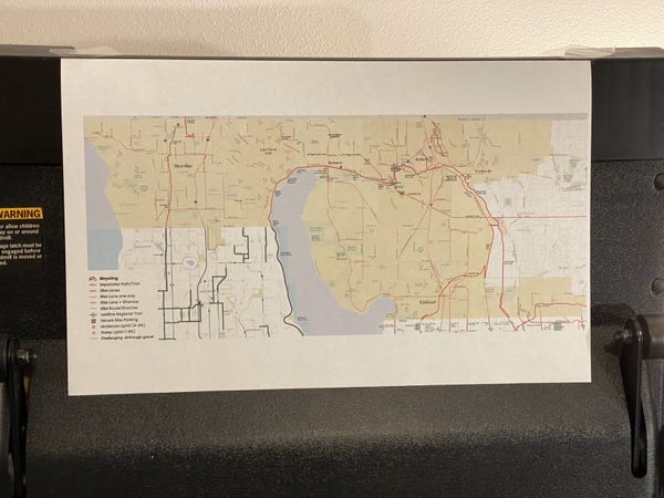 A printout of the northshore connector bike map I made onto 11x17 paper, hung up flat on a black folded-up treadmill 