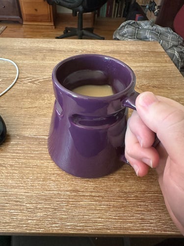 Hand holding a deep space purple coffee mug.
