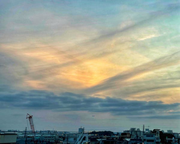 Urban skyline during sunset with colorful clouds and a crane visible against the evening sky over Urasoe in Okinawa, Japan.