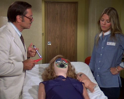 Still scene from an episode of The Bionic Woman, with Dr. Rudy Wells and Jamie Sommers examining a fembot.