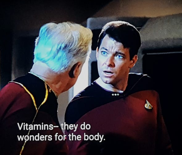 TNG scene. We're on ship and looking at Riker and a much older man, both in uniform, arguing. Riker has a wtf look on his face in response to whatever the older fella is saying. Closed caption reads, "Vitamins - they do wonders for the body."