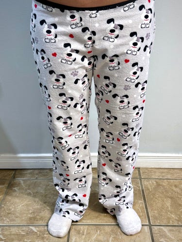 A petite woman wearing a basted pair of dog print flannel pyjamas.