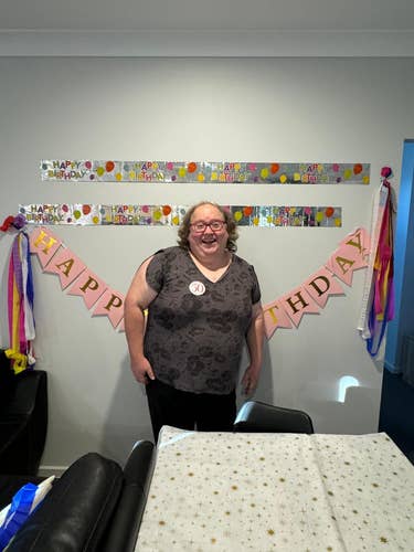 Me (Jo) standing in front of wall decorations that say Happy Birthday. 