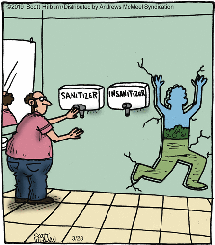 In a public toilet, a man is using a sanitizer, while next to him, someone has used the insanitizer and has smashed through the wall.