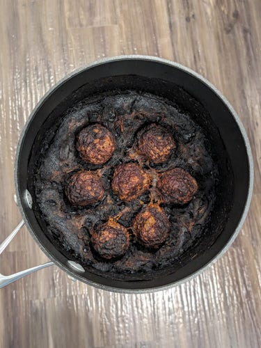 A photo of a pot of meatballs in sauce that has been cooked to the point of being black