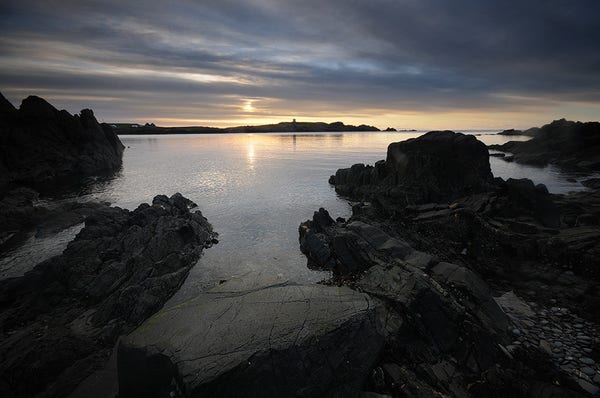 Image of sunrise over a rocky shoreline.