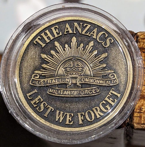 Medallion with THE ANZACS above and LEST WE FORGET below with the rising sun insignia of the "Australian Commonwealth Military Forces"