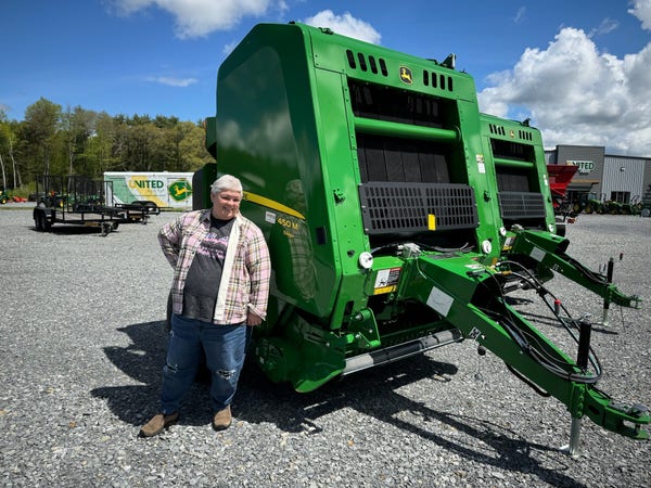 I’m standing next to a very large John Deere silage bailer. The machine is nearly twice as tall as I am. I’m wearing a pink plaid fleece-lined flannel, a Critical Role Scanlan tour t-shirt, and decoratively holey jeans. It’s an interesting juxtaposition. (I am also smiling hugely.)