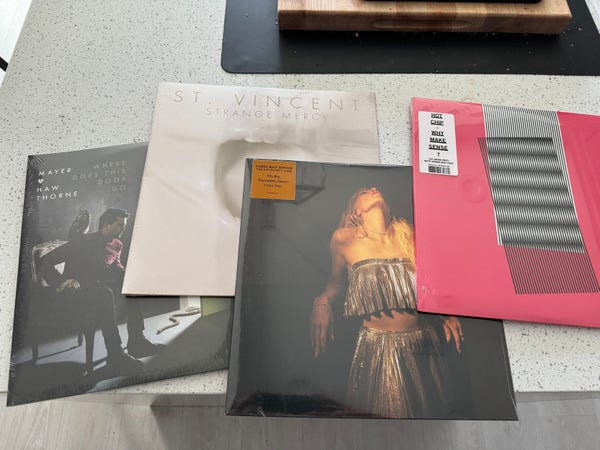 Four albums sealed in plastic stacked partially on top of each other on a counter top. They are from left to right: “Where Does This Door Go?” by Mayer Hawthorne, “Strange Mercy” by St. Vincent, “The Loveliest Time” by Carly Rae Jepsen, and “Why Make Sense?” by Hot Chip. 
