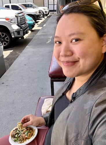 A photo of a person looking really happy holding tacos outside an East LA taqueria 