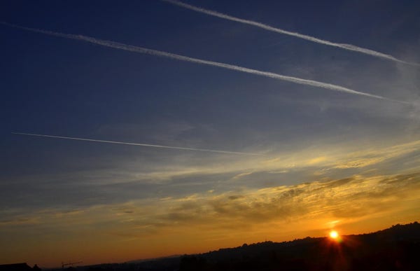 Photograph of a sunset featuring three parallel vapour trails.