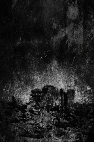 Black and white image of a rocky outcrop, under dark dramatic skies. Photo with textured overlays.