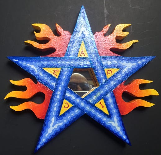 Blue pentagram with red and yellow stylized flames, the word magic, and a mirror in the center.
