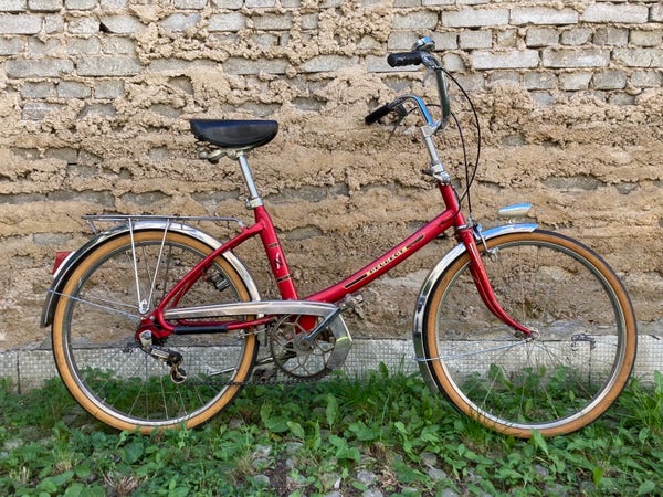 Un vélo rouge des années 70 avec ses jolis chromes, le long d’un mur