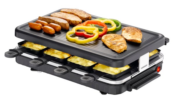 A picture of a Raclette grill, loaded with pans below and meat and veggies on the top. 