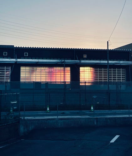 This photo shows something orange shining brightly inside a flat factory with a tin roof. The time of the setting sun.
The inside of the factory and the sky outside of it were orange.
